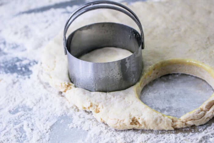 Biscuit dough from the Hardees Biscuits recipe is shaped with a round cutter on a floured surface.