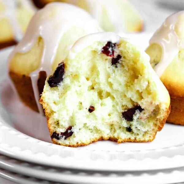 A healthy cranberry muffin with yogurt and glaze, cut in half, sits invitingly on a white plate.