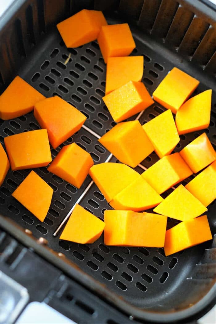 Air fryer butternut squash cubes sit in the basket, perfectly prepped and ready to roast.
