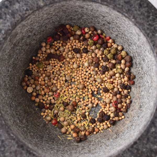 A variety of whole spices in a stone mortar, perfect for crafting your own corned beef spice recipe.