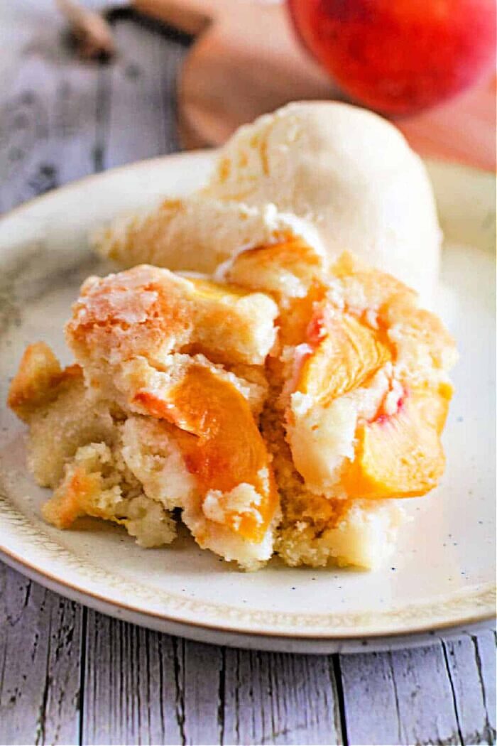 A plate of fresh peach dump cake with a scoop of vanilla ice cream complements the flavors as beautifully as a fresh fruit cake.