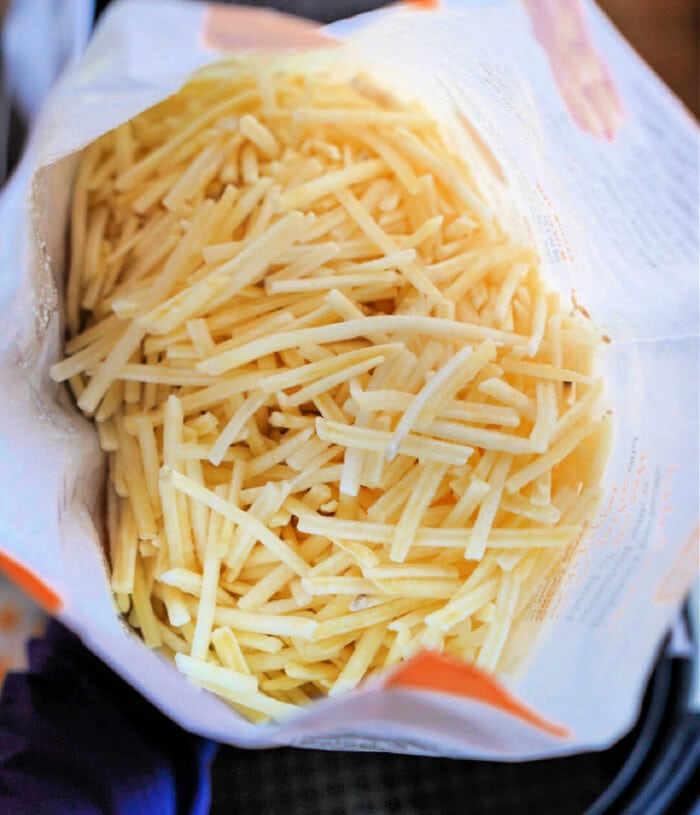 Overhead view of a bag of frozen hashbrowns, partially opened, as if ready to be the perfect crunchy topping for a warm hashbrown soup.