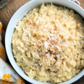 A bowl of creamy rice pudding, effortlessly crafted using instant pot dessert recipes, is topped with shredded coconut and a sprinkle of cinnamon.