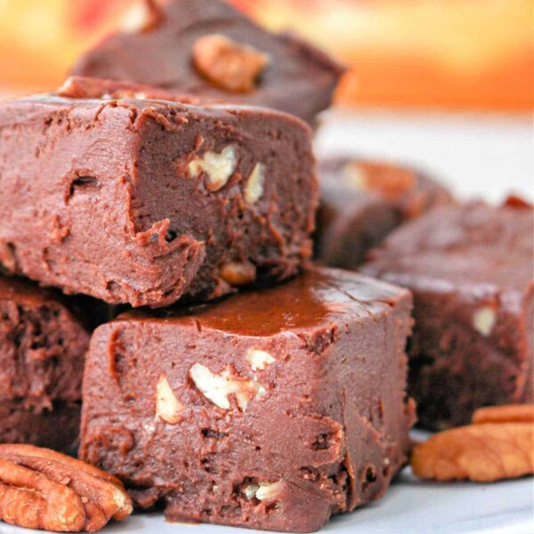 Close-up of chocolate fudge with Velveeta and pecan pieces stacked on a plate.