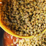 A close-up image shows a yellow strainer filled with cooked green lentils being added to a pot of simmering tomato-based sauce. At the top, the text reads, "How Long to Cook Lentils on Stove" in bold black and white font.