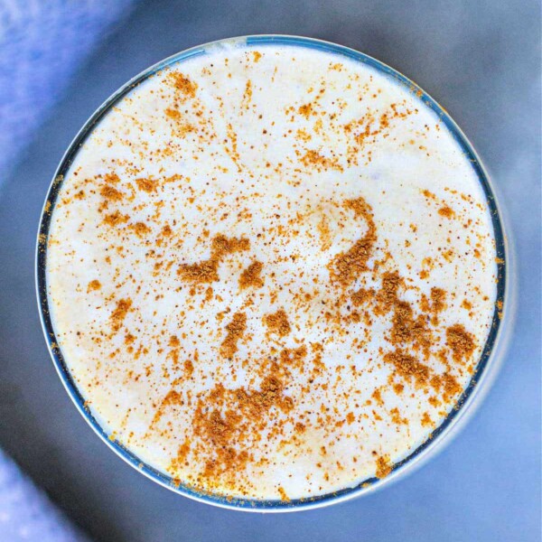 Top view of a creamy drink in a glass, sprinkled with cinnamon, infused with pumpkin cream cold foam.