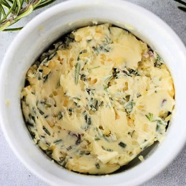 Cowboy butter recipe: Herb-infused butter in a white ramekin, garnished with fresh rosemary sprigs.