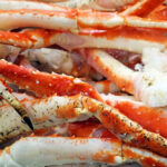 A pile of frozen red and white crab legs rests on ice, perfect for anyone curious about how to cook frozen crab legs to perfection.