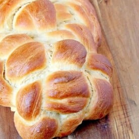 Close-up of freshly baked challah with a golden crust on a wooden board, showcasing the beauty of this traditional braided bread.