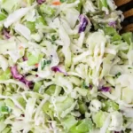 A bowl of coleslaw is shown, labeled "4 Ingredient cole slaw." The coleslaw contains shredded cabbage, chopped green parts, and visible specks of purple cabbage and a white creamy dressing, mixed together to form the salad—an ideal Cole Slaw Recipe for Pulled Pork.