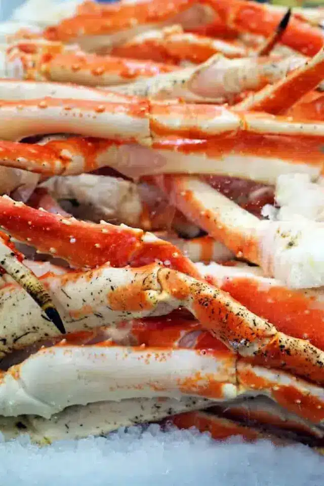 A close-up view of a pile of red and white crab legs on ice, showcasing their texture and colors. 