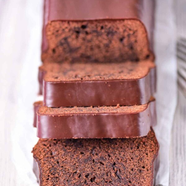 Sliced brownie loaf cake, reminiscent of a rich brownie bread, rests on a wooden surface.