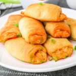 A plate of golden-brown Buffalo Chicken Rolls sits invitingly, with a dipping sauce in the background.