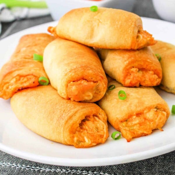 A plate of golden-brown Buffalo Chicken Rolls sits invitingly, with a dipping sauce in the background.