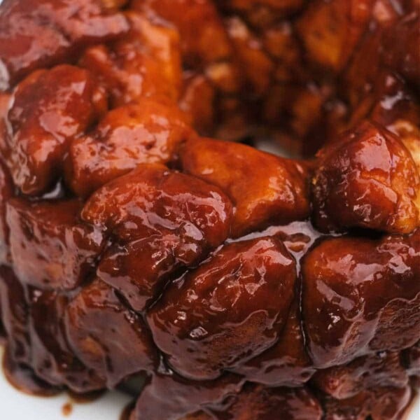 Close-up of glazed monkey bread made from a canned cinnamon roll recipe on a white plate.