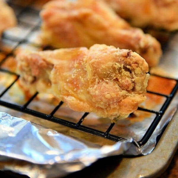 Close-up of irresistible, crispy chicken wings baked to perfection on a cooling rack with foil underneath, showcasing the secret of how to bake crispy chicken wings effortlessly.