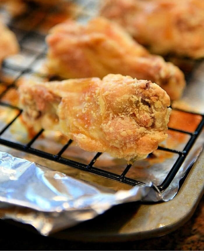 Close-up of irresistible, crispy chicken wings baked to perfection on a cooling rack with foil underneath, showcasing the secret of how to bake crispy chicken wings effortlessly.