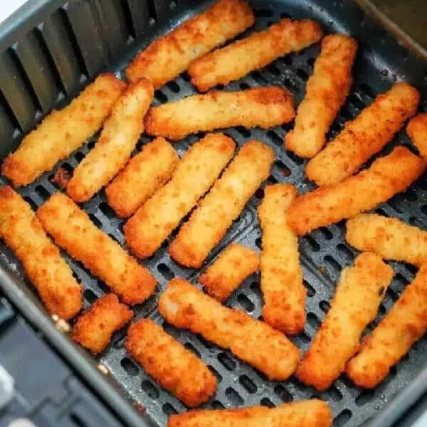 Crispy golden brown air fryer fish sticks are arranged inside an open basket, ready to be served.