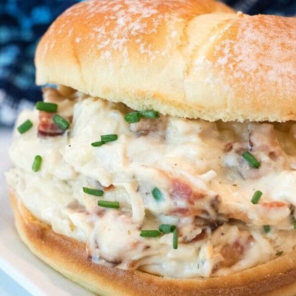 Savor the best crockpot chicken recipe with our creamy chicken and bacon sandwich, topped with freshly chopped chives on a soft bun.