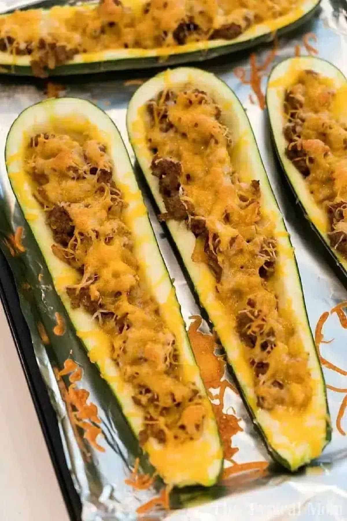 Air fryer zucchini boats stuffed with ground meat and melted cheese, baked to perfection on a foil-lined tray.