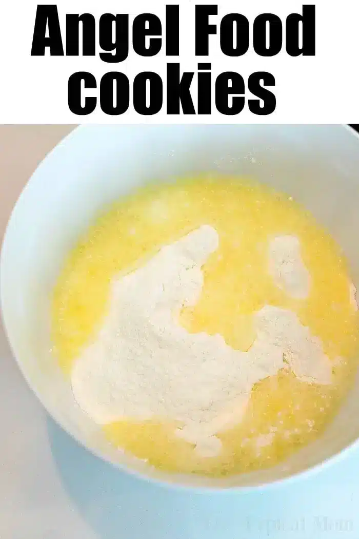 A white mixing bowl containing yellow, melted butter and white, powdered ingredients.