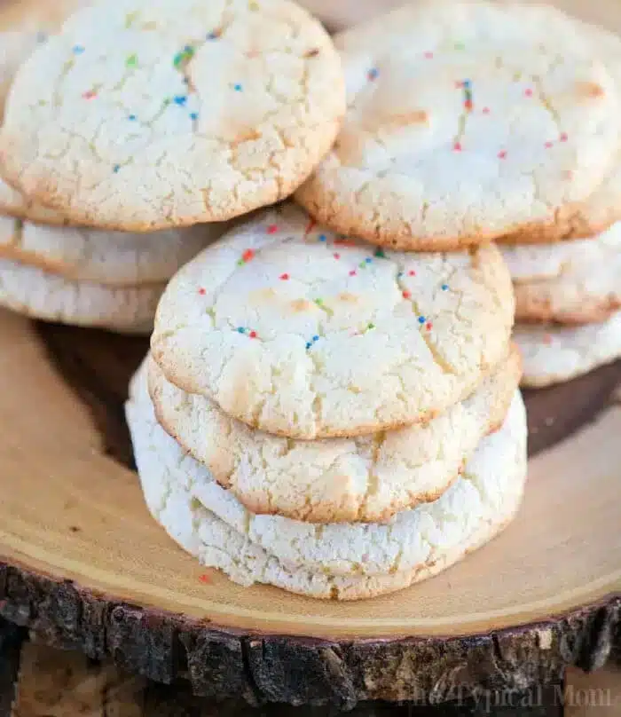 A stack of six sugar cookies made from angel food cake mix with rainbow sprinkles sits on a wooden platter.