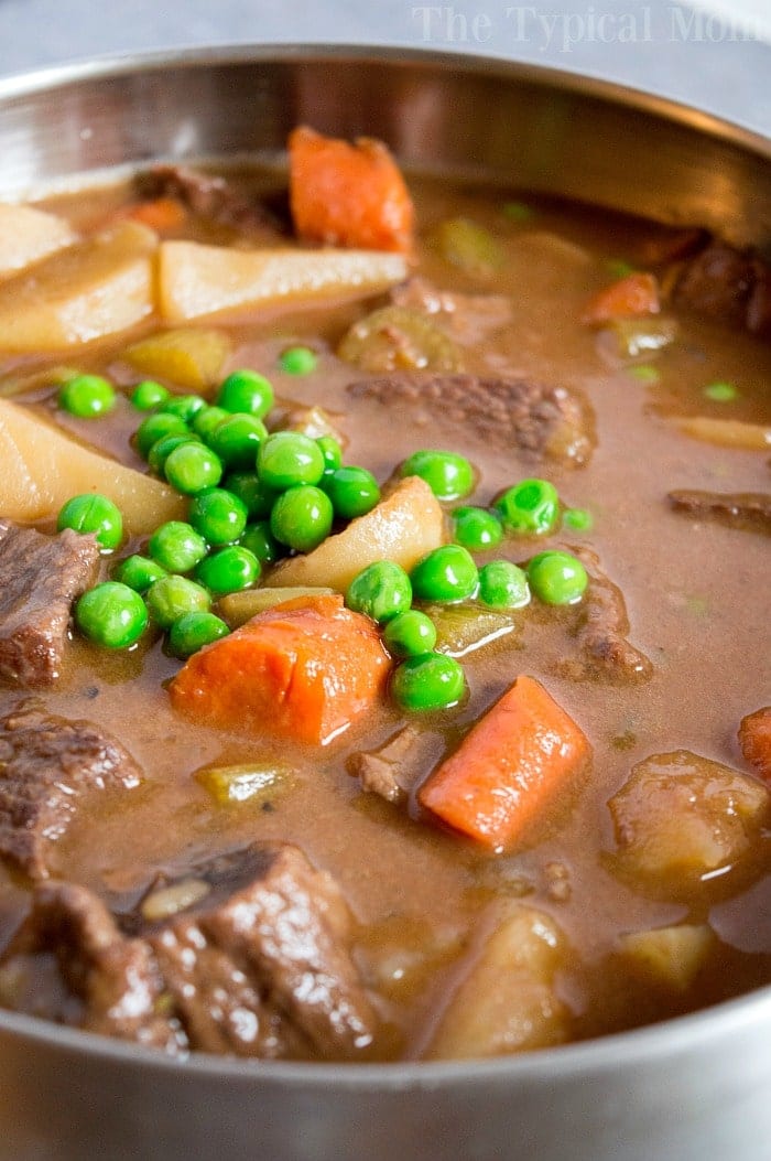 Close-up of a hearty beef stew cooked to perfection in a Dutch oven, with chunks of beef, carrots, potatoes, and peas swimming in a rich broth.