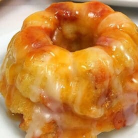 Mini bundt cake topped with a thick, glossy caramel and white icing, reminiscent of a classic caramel apple bread pudding, served on a white plate.