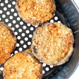 Four air fryer stuffed mushrooms with a golden breadcrumb topping served fresh from the basket.