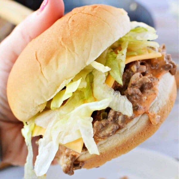 A hand holds a Big Mac, brimming with lettuce and juicy ground beef.