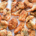 Crispy, golden-brown air fryer popcorn chicken pieces arranged on a white surface.