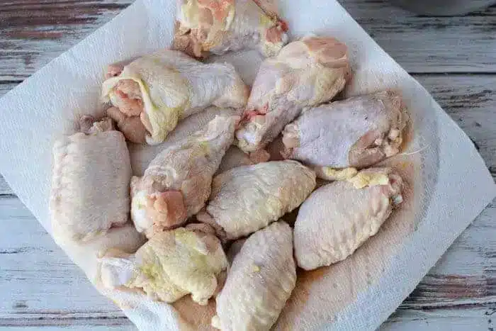 Several raw chicken wings placed on a paper towel, to dry.