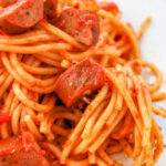 A plate of sausage spaghetti adorned with rich tomato sauce and perfectly sliced sausages.