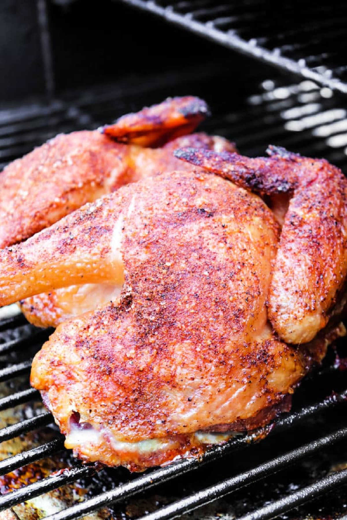 Smoked Spatchcock Chicken with crispy skin and visible grill marks, seasoned to perfection and smoked whole on a grill.