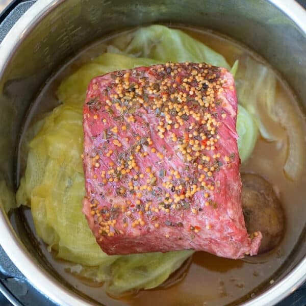 Instant Pot corned beef and cabbage, seasoned with savory spices and simmering in rich broth, ready to be cooked for a hearty meal.