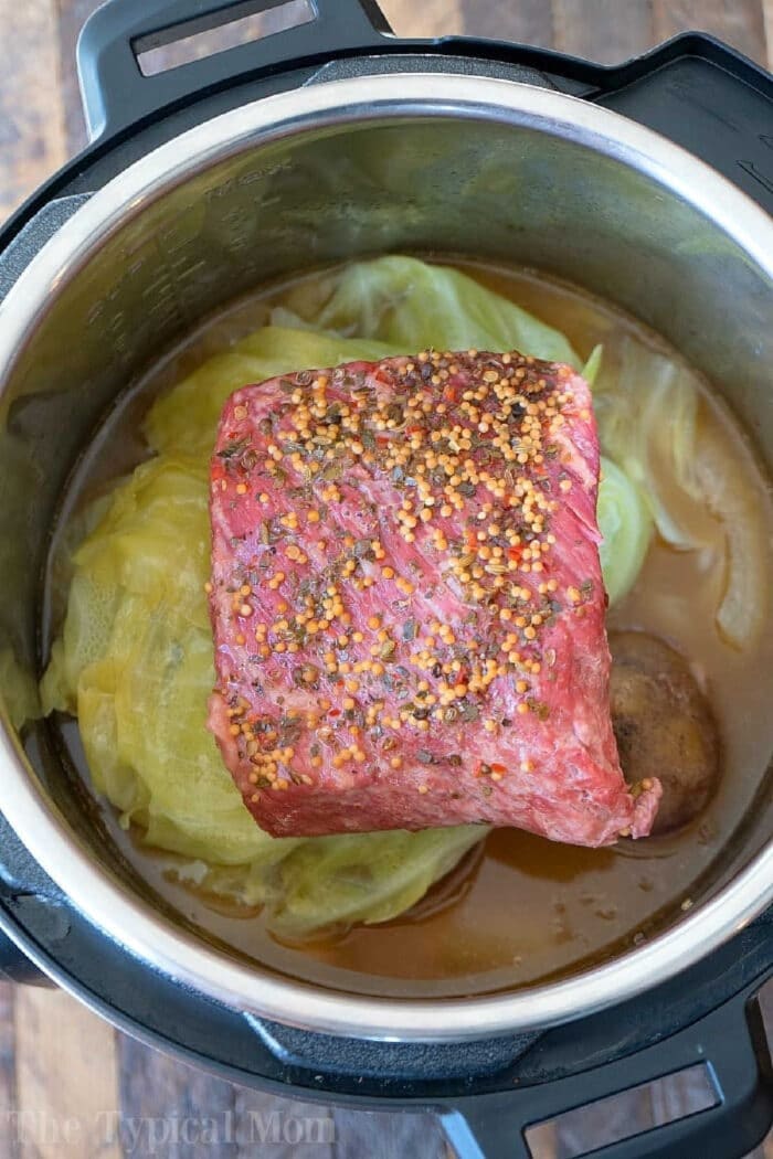 Easy Instant Pot corned beef and cabbage is perfect for St. Patrick's Day or any other day of the year! Moist and flavorful corned beef brisket cooked in your pressure cooker is simple to do with a potato trick I use quite often. If you haven't tried this dinner idea you're in for a treat. #instantpotrecipes #cornedbeefandcabbage #pressurecooker #cornedbeef #brisket #cabbage #crockpotexpress #ninjafoodirecipes Instant Pot corned beef and cabbage, seasoned with savory spices and simmering in rich broth, ready to be cooked for a hearty meal.