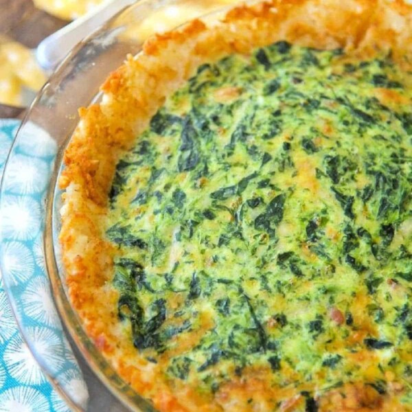 A freshly baked spinach and cheese quiche in a glass pie dish, showcasing an easy spinach quiche recipe, surrounded by colorful napkins.