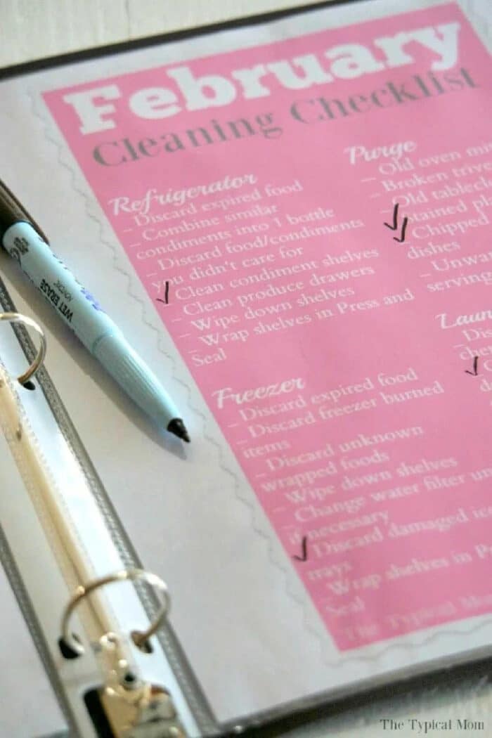 A February cleaning checklist is neatly displayed in a home organization binder, with a pen resting on the open page, ready for your next task.