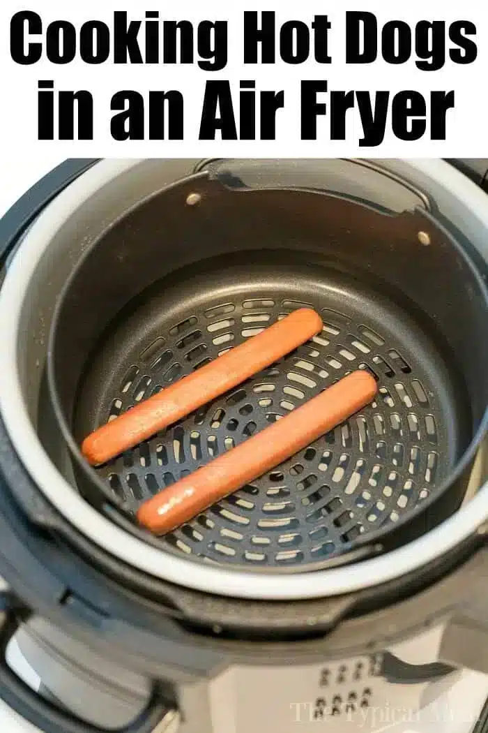 Air fryer with two uncooked hot dogs inside. The text above the air fryer reads "Cooking Hot Dogs in an Air Fryer." The sleek black air fryer basket is clean and well-maintained.