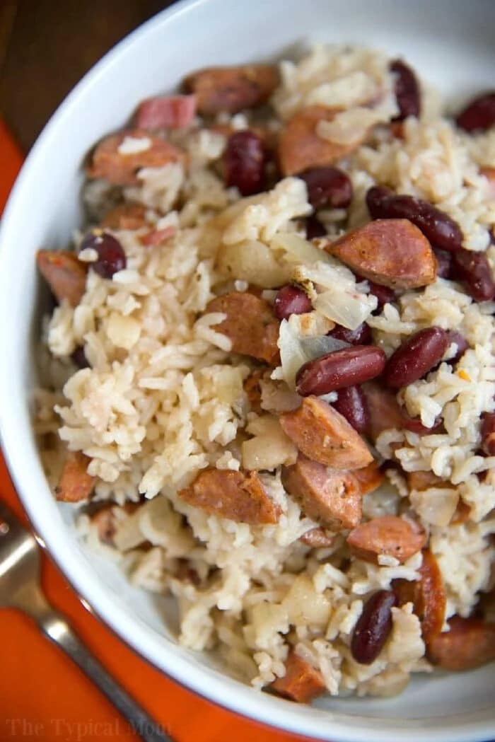 The best Instant Pot red beans and rice recipe ever! Really easy to make and cheap too. Great pressure cooker dinner idea that's hearty and packed with lots of flavor. Using uncooked rice and a few other ingredients it's a one pot meal my kids absolutely love. #instantpot #pressurecooker #redbeansandrice #red #beans #sausage #rice #easy A bowl of rice mixed with kidney beans, chopped sausage, and onions—just like a classic instant pot red beans and rice recipe.