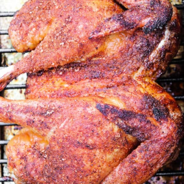 Smoked Spatchcock Chicken, spiced and roasted on a metal rack, golden and crispy, viewed from above.