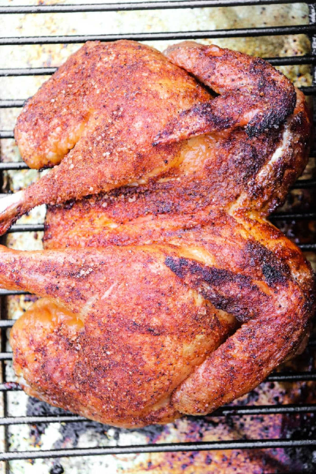 Smoked Spatchcock Chicken, spiced and roasted on a metal rack, golden and crispy, viewed from above.