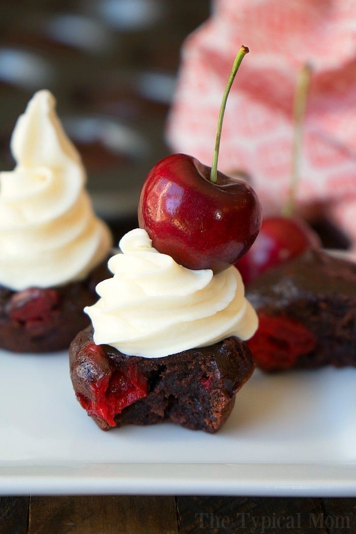 Chocolate cherry cupcakes with white frosting and topped with a fresh cherry on a white plate make the perfect football party food, adding a sweet touch to the festivities.