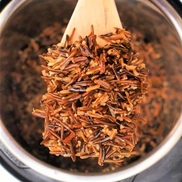 A wooden spoon lifts cooked wild rice from a Black Rice Instant Pot.