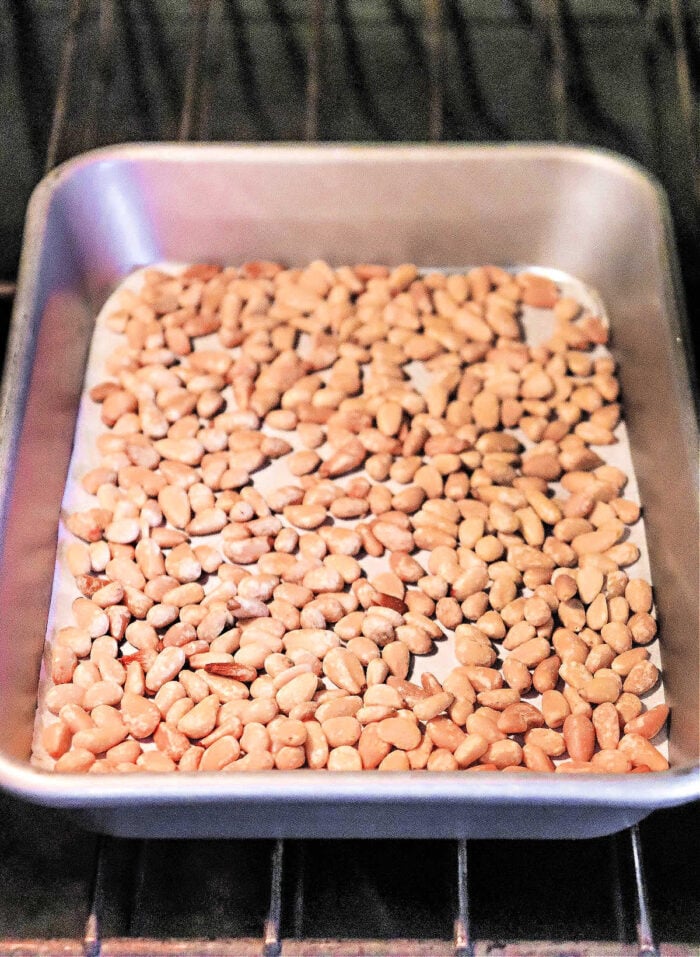 How to Roast Pine Nuts: Pine nuts spread on a baking sheet in the oven, perfectly arranged and ready for roasting.