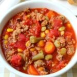 Enjoy a comforting bowl of crock pot vegetable beef soup, filled with corn, carrots, green beans, tomatoes, and savory ground beef in a hearty red broth.