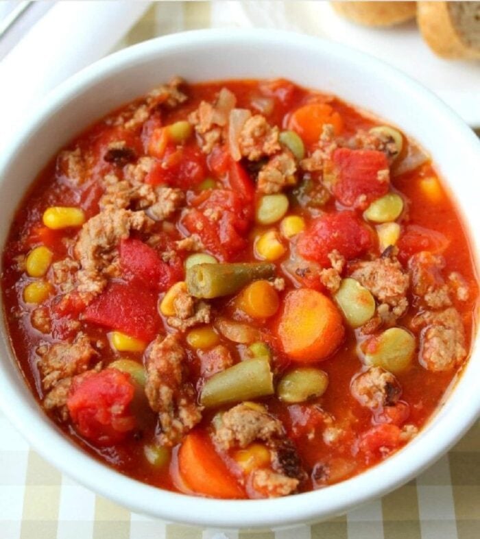 Enjoy a comforting bowl of crock pot vegetable beef soup, filled with corn, carrots, green beans, tomatoes, and savory ground beef in a hearty red broth.