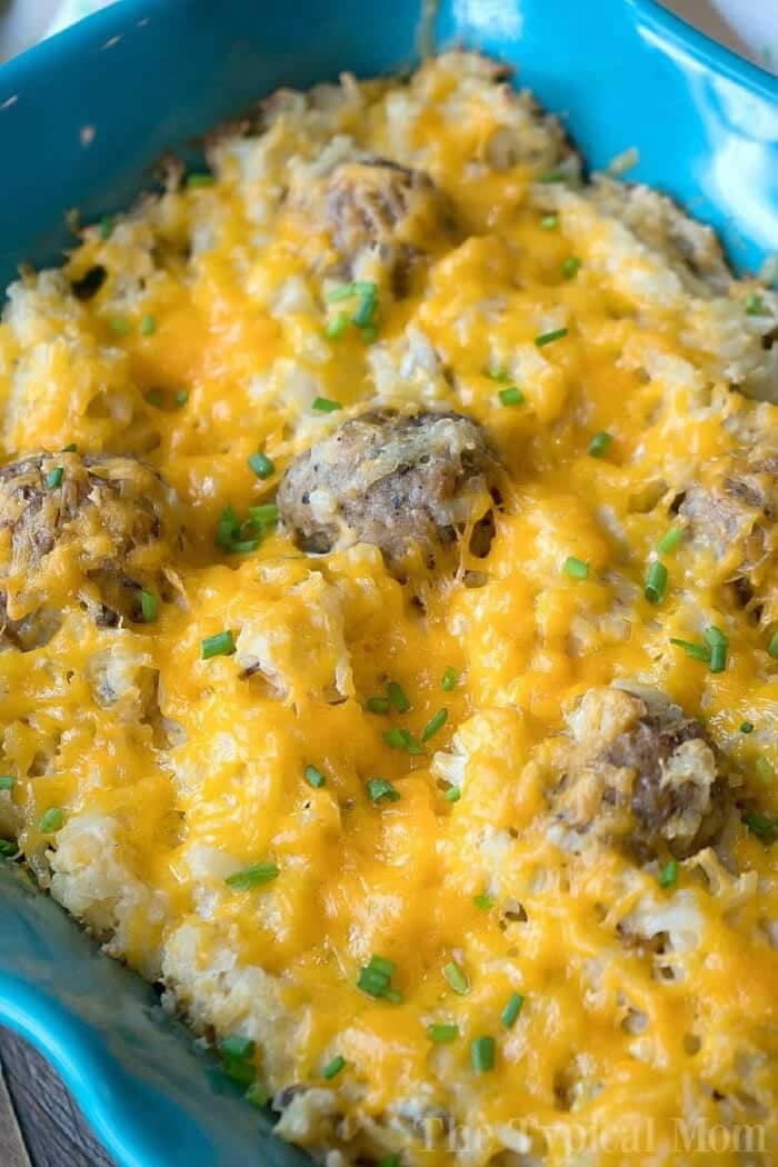 This hamburger hashbrown casserole with sour cream recipe is the perfect brunch or Christmas morning breakfast idea! Hearty meal we love year round. Baked hamburger hashbrown casserole with sour cream, melted cheese, savory meatballs, and chopped chives in a blue dish.