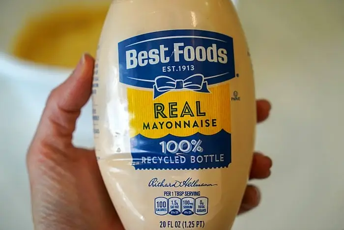 A person holds a 20 fl oz bottle of Best Foods Real Mayonnaise, labeled "100% Recycled Bottle." Perfect for crafting the ultimate bang bang shrimp sauce, this mayo offers 100 calories per tablespoon serving and nutrition facts right on the label.