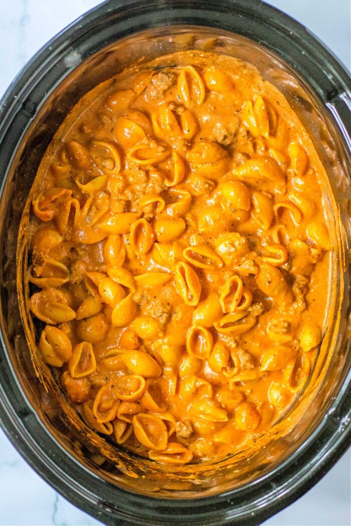 Shell pasta in creamy orange sauce, reminiscent of goulash in the Crock-pot, viewed from above.